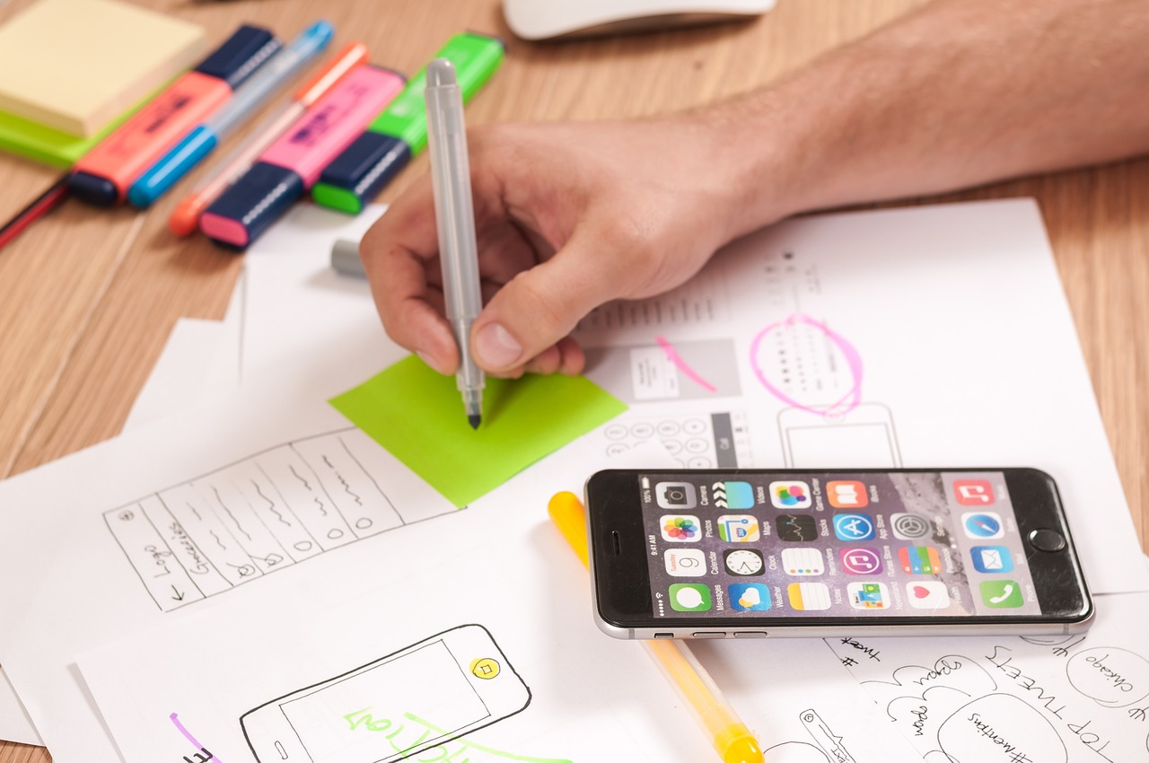 Designer sketching a UX wireframe on paper and screen